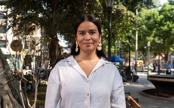 Portrait of a woman in a sunny urban park in Piura, Peru, exuding confidence.